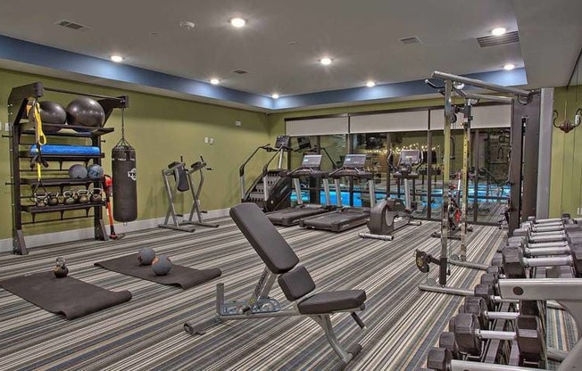a gym with a lot of chairs and weights at Hunters Creek Apartments, Denton