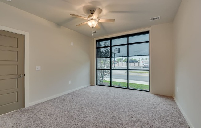 an empty bedroom with a large window and a ceiling fan at The Augustan, Augusta