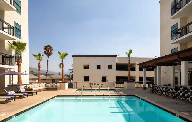 A swimming pool in front of a white building with palm trees in the background.
