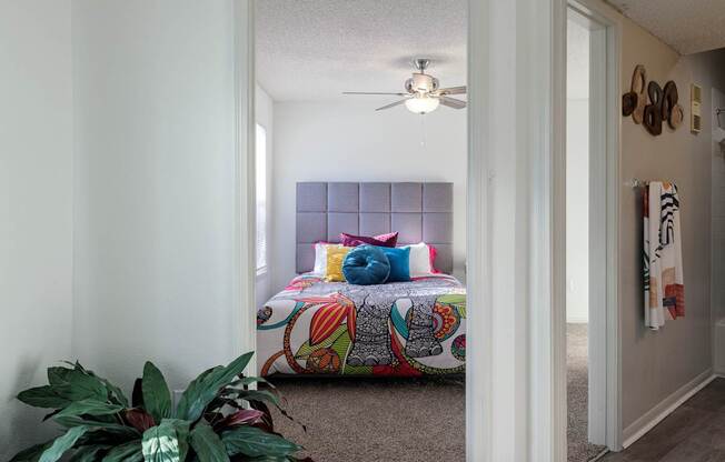 A cozy bedroom in the model unit of Skyler Ridge Apartments, featuring a bed and ceiling fan.