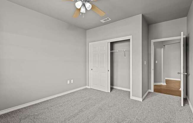 A room with a ceiling fan and carpeted floor.
