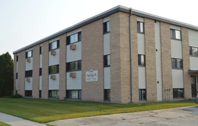 a brick building with a sign on the side of it. Fargo, ND Spring Apartments