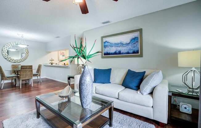 A living room with a white couch and a glass coffee table.