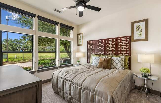 A bedroom with a large bed and a ceiling fan.