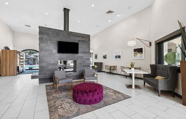 A modern living room with a stone fireplace and a purple ottoman.