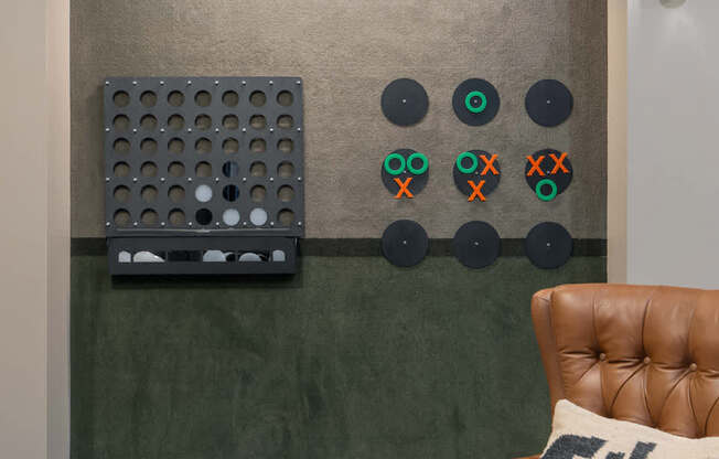A brown leather chair with a pillow on it in front of a wall with a green board and some circles on it.