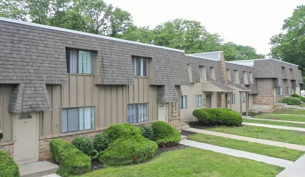 a row of apartment buildings with green grass and sidewalks