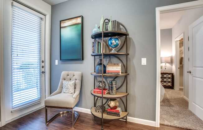 a living room with a chair and a shelf with books