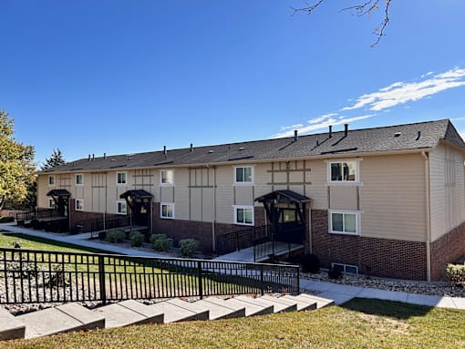 an apartment building with a yard and a black wrought iron fence