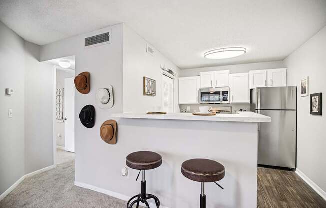 A kitchen with a white counter and two stools.