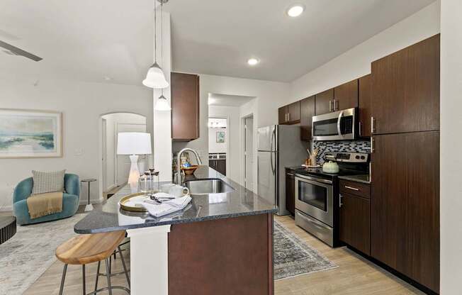 A modern kitchen with dark wood cabinets and stainless steel appliances.