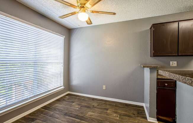 A room with a ceiling fan and a window with blinds.