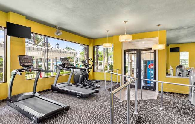 A gym with treadmills and a television.