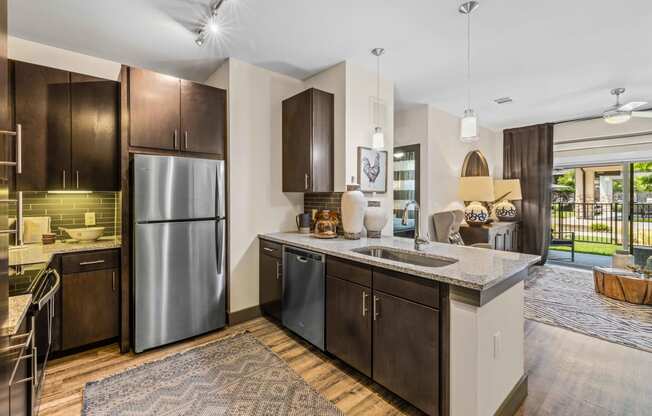 model kitchen overlooking living room. Stainless steel appliances and espresso cabinetry