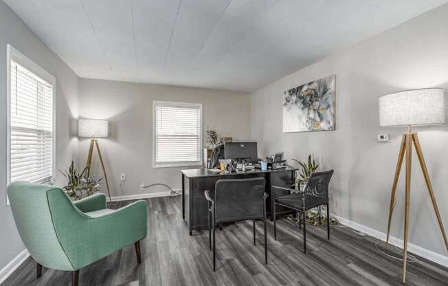 A room with a green chair and a desk with a laptop and other items on it.