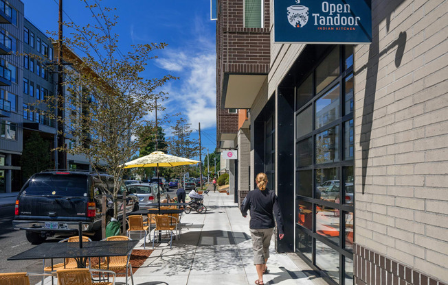 a man walking down a sidewalk in front of a restaurant