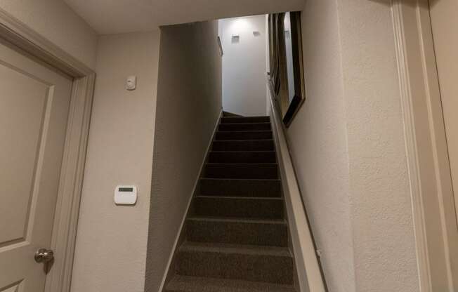 This is a photo of the entryway stairs to the second floor and the door to the attached, direct-access garagein the 826 square foot 1 bedroom , 1 bath apartment at The Brownstones Townhome Apartments in Dallas, TX.