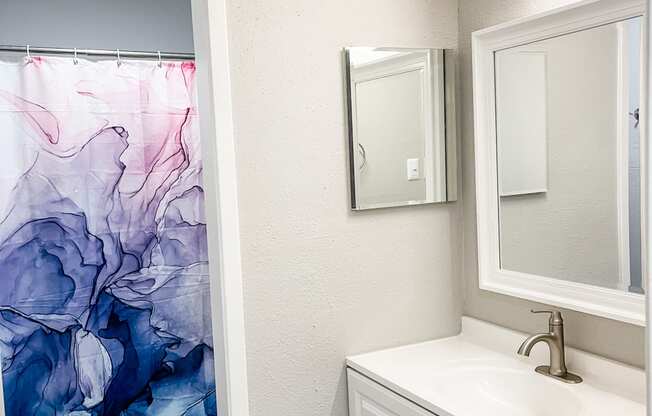 a bathroom with a sink and a mirror and a shower curtain