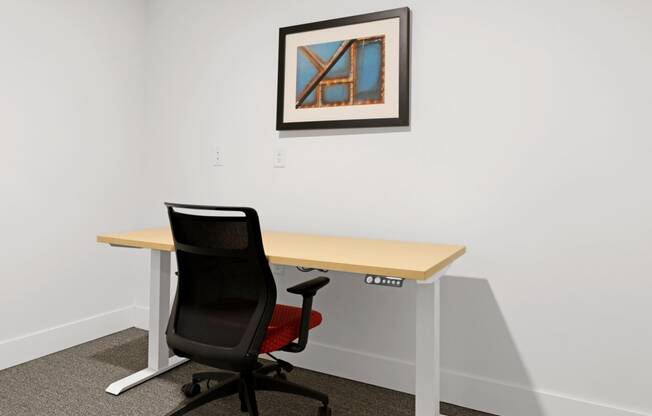 a desk with a chair and a picture on the wall