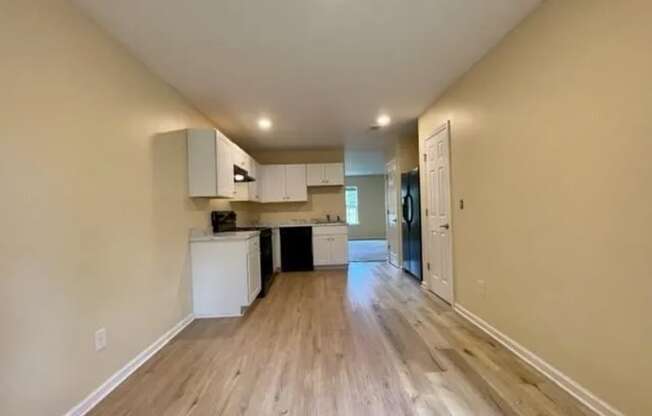 an empty living room and kitchen with wood floors