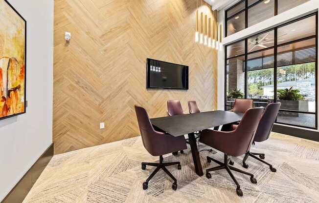 A conference room with a table and chairs and a TV on the wall at Preston Ridge Apartments.