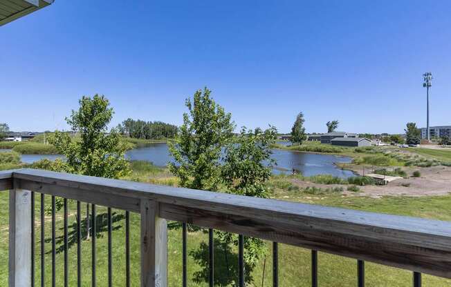 A balcony overlooks a river and a field.