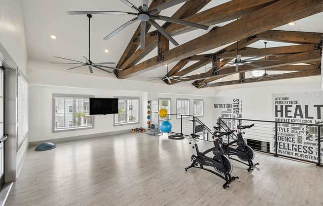 a workout room with exposed ceiling beams and a tv