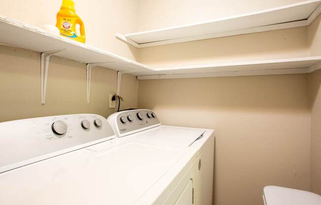 A yellow bottle of detergent is on top of a white washing machine.