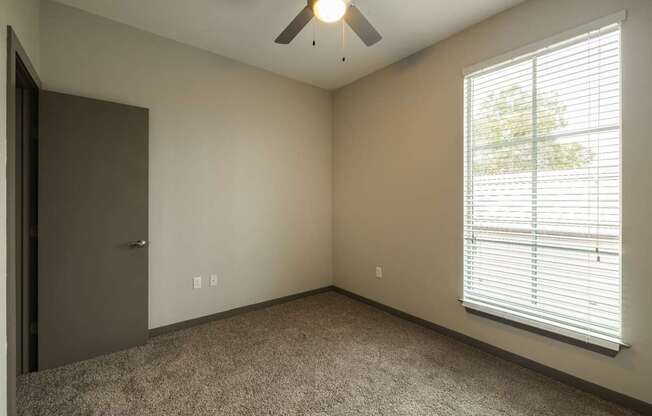 A room with a ceiling fan and a window with blinds.