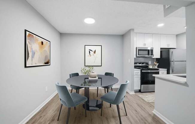 A modern dining room with a round table and grey chairs.