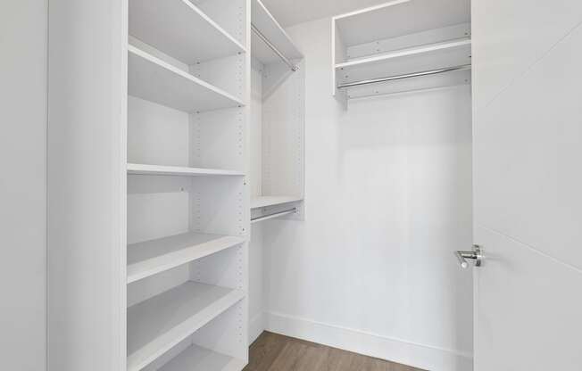 Large walk-in closet with built-in shelving at MB Station apartments in Miami, offering generous storage and organized living space.