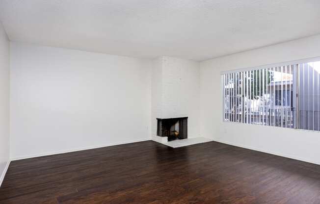 an empty living room with wood floors and a fireplace