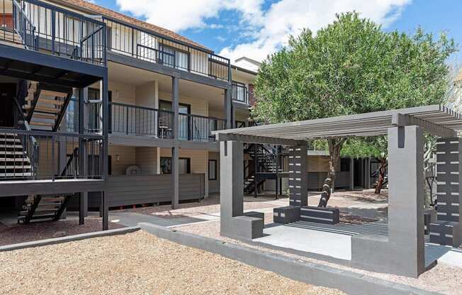 A modern building with a balcony and a tree in the background.