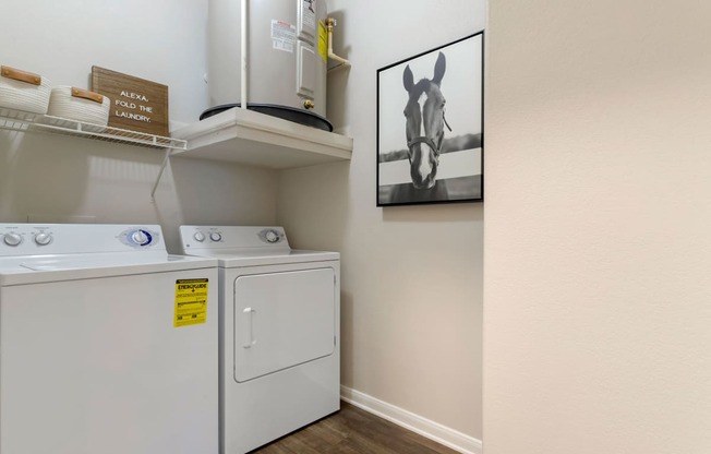a laundry room with a washer and dryer and a painting on the wall at Madison on the Meadow, Stafford, Texas