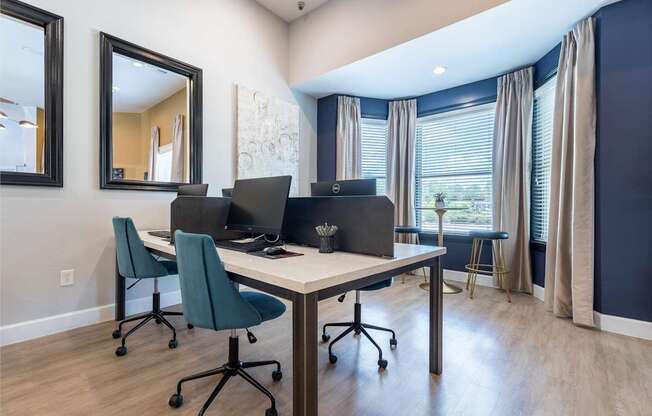 A room with a desk, chairs, and a mirror.