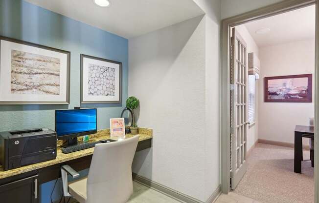 A room with a desk, chair, and printer.