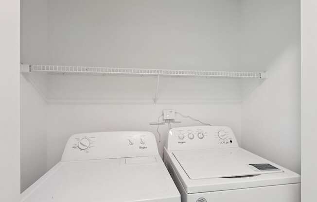Two white washing machines in a small laundry room.