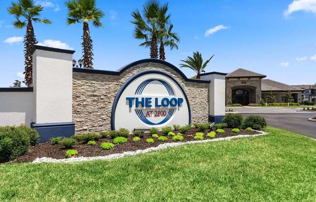 A sign for The Loop at 2700 with a blue sky and palm trees in the background.