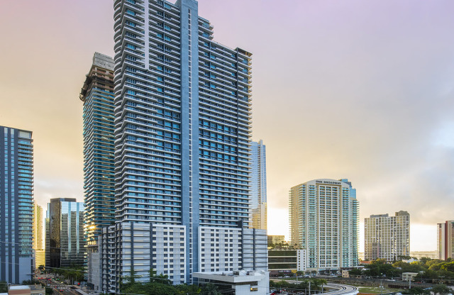Photograph of The SOMA at Brickell Apartment complex, featuring a cloudy sky and view of the Miami skyline.