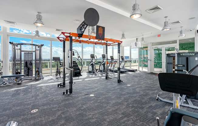 A gym with a variety of equipment including a squat rack, bench press, and a rowing machine.
