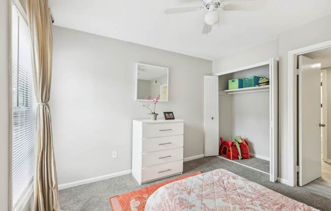 A bedroom with a dresser, mirror, and a ceiling fan.