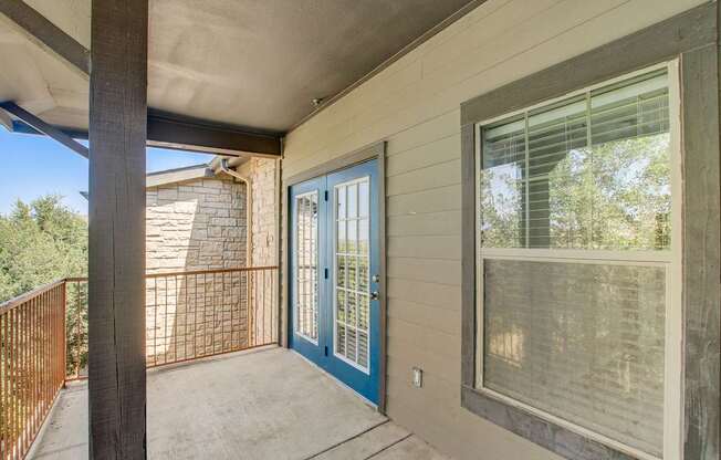 A balcony with a blue door and a window.