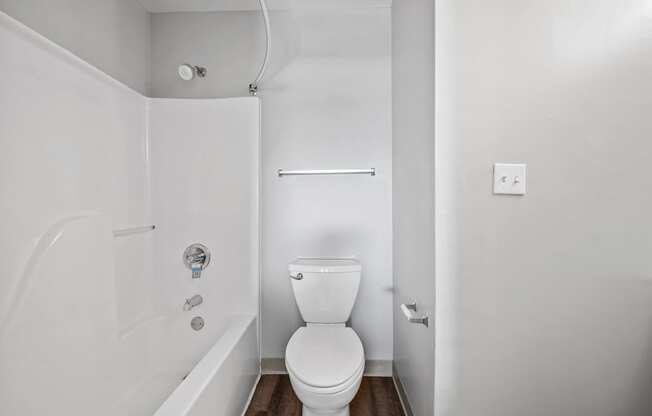 A white bathroom with a toilet, tub, and shower.