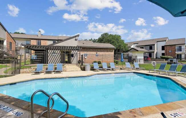 A swimming pool with a metal ladder at The Oaks of Denton Apartments in Denton, TX