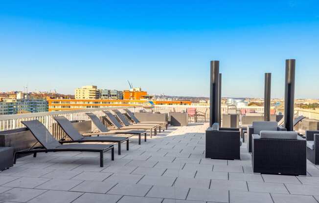 a row of lounge chairs on a rooftop patio overlooking the city