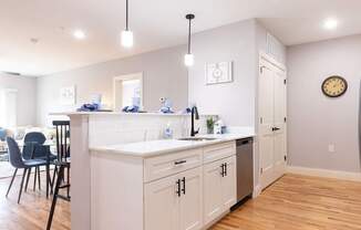 A kitchen with white cabinets and a wooden floor.