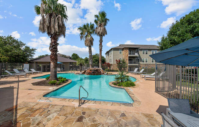 a swimming pool with palm trees and a building in the background