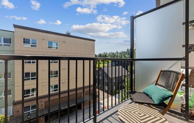 A balcony with a chair and a table with a white screen on the right.