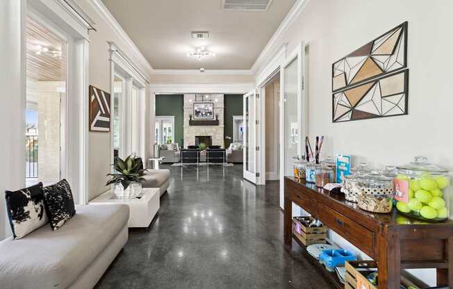 A long hallway with a white sofa and a wooden table with many items on it.