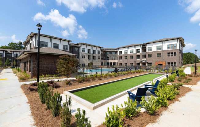 a courtyard with a lawn and chairs in front of an apartment building